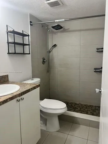 a bathroom with a granite countertop toilet a sink and shower