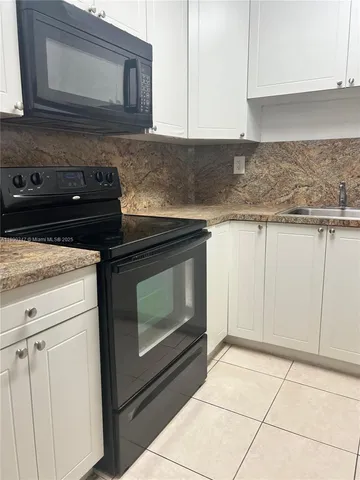 a kitchen with granite countertop white cabinets and white appliances