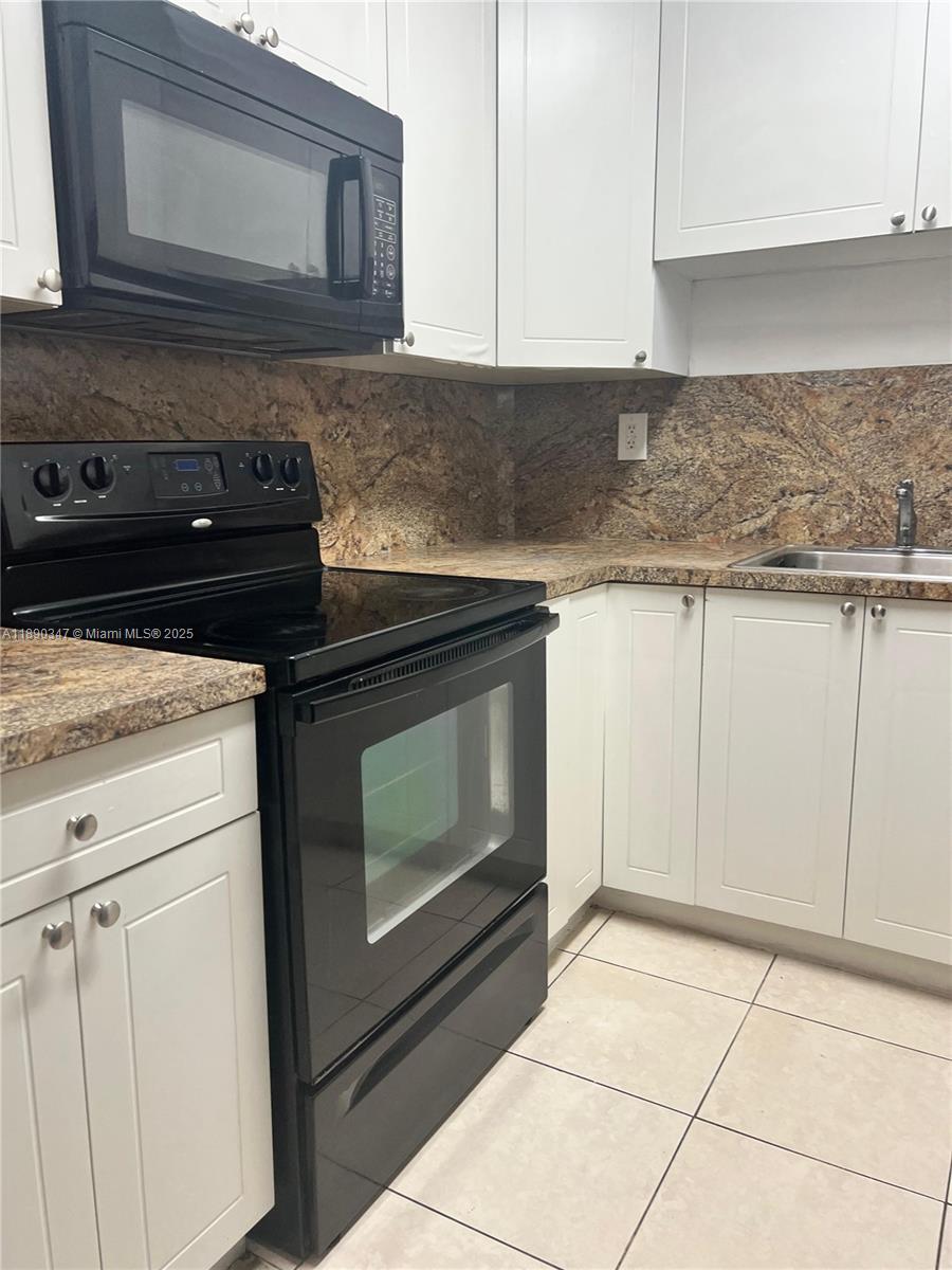 1875 West 56th Street, Unit 103 Hialeah, FL 33012 - Photo 5 of 13 a kitchen with granite countertop white cabinets and white appliances