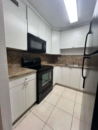a kitchen with granite countertop a sink a stove top oven and cabinets