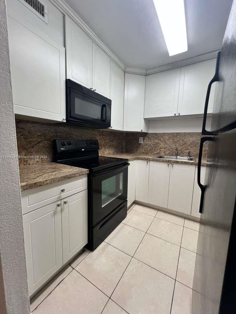 1875 West 56th Street, Unit 103 Hialeah, FL 33012 - Photo 6 of 13 a kitchen with granite countertop a sink a stove top oven and cabinets