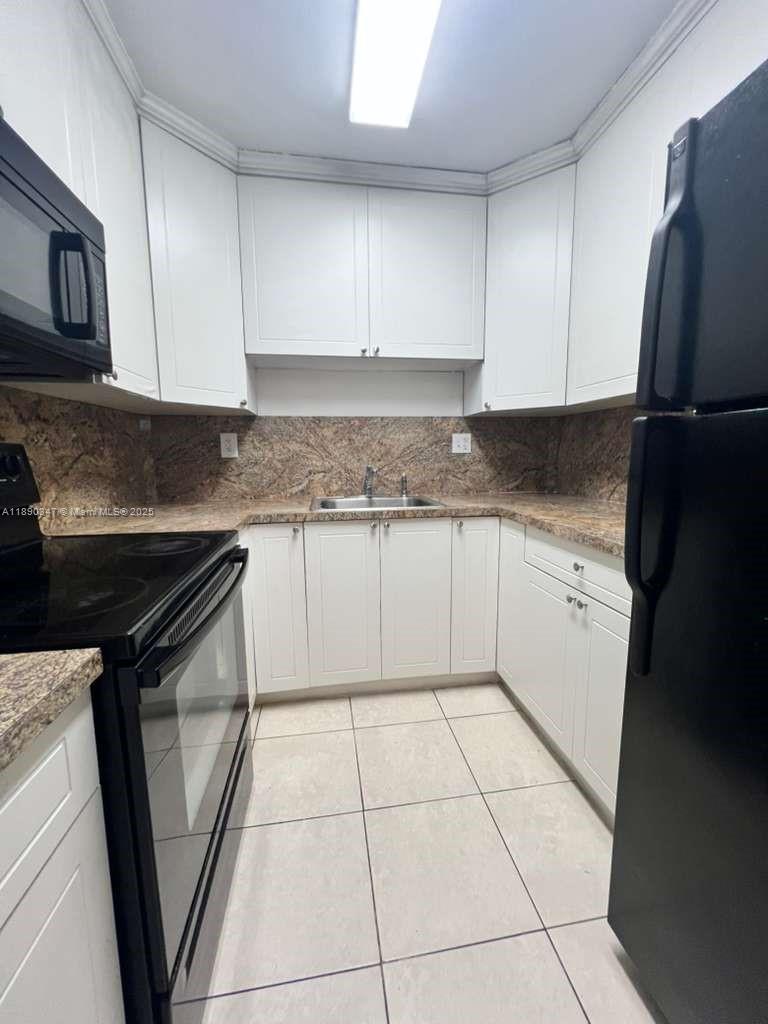 1875 West 56th Street, Unit 103 Hialeah, FL 33012 - Photo 7 of 13 a kitchen with a sink a stove top oven a refrigerator and cabinets