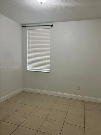 an empty room with a white cabinet and a window