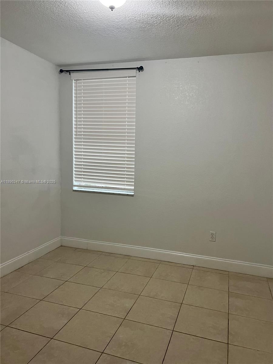1875 West 56th Street, Unit 103 Hialeah, FL 33012 - Photo 9 of 13 an empty room with a white cabinet and a window