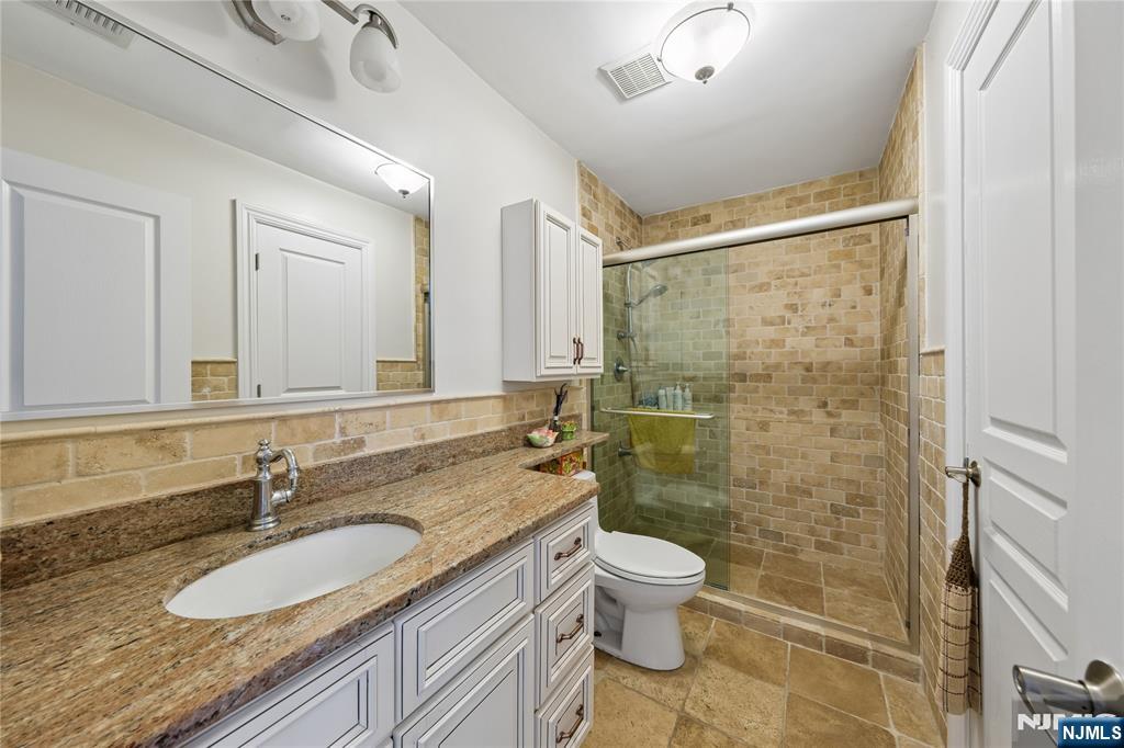 93 Jackson Drive Cresskill, NJ 07626 - Photo 20 of 37 a bathroom with a granite countertop sink a toilet a mirror and shower