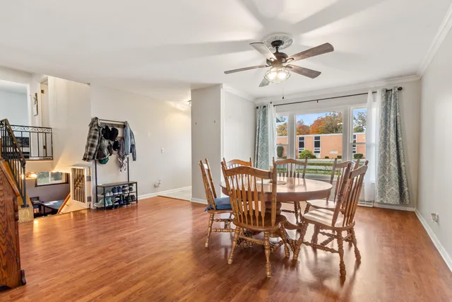 a dining room with wooden floor a chandelier fan a wooden table and chairs
