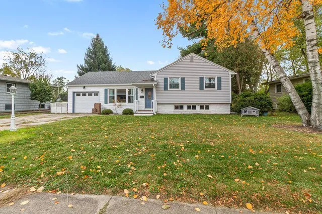 a front view of a house with a yard and trees
