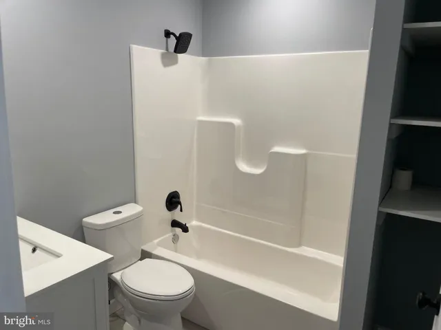 a white toilet sitting next to a bath tub