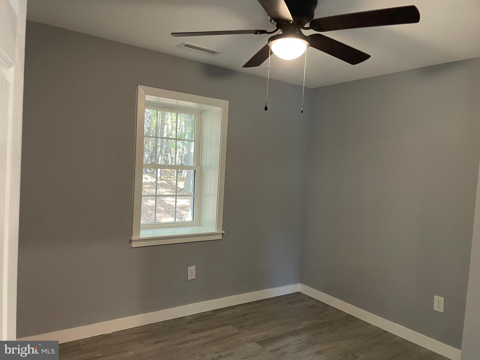 5051 Wayman Road Marion Station, MD 21838 - Photo 9 of 13 an empty room with wooden floor fan and windows