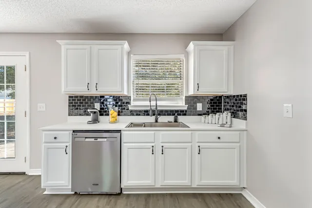 a kitchen with white cabinets and sink