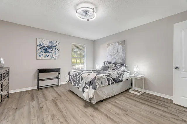 a bed sitting in a bedroom next to a window and a wooden floor