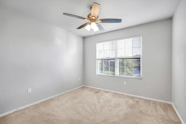 an empty room with a window and a fan