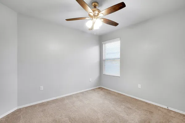 an empty room with a window and a fan