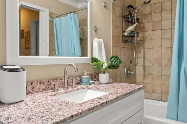 a bathroom with a granite countertop sink a mirror and shower