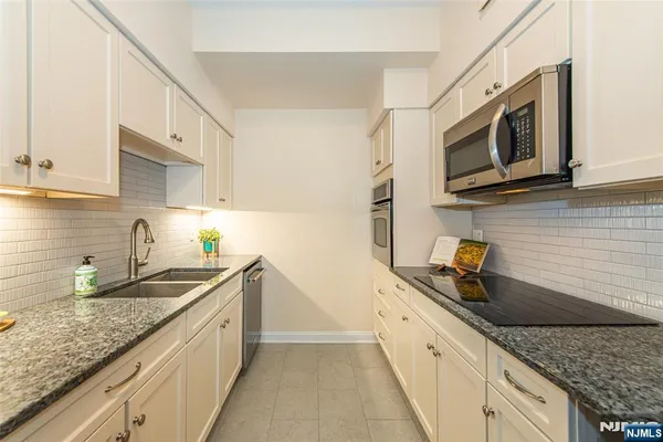 a kitchen with stainless steel appliances granite countertop a sink a stove microwave and cabinets