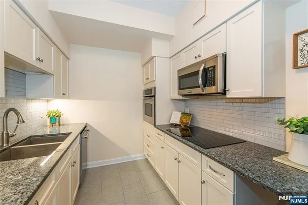 a kitchen with granite countertop a sink a stove and microwave