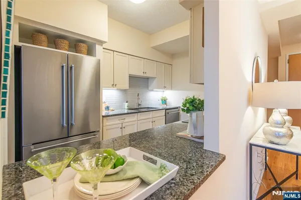 a kitchen with stainless steel appliances granite countertop a refrigerator a sink a stove and white cabinets