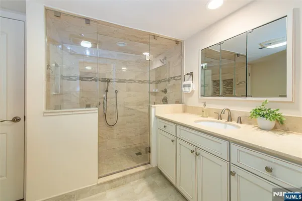 a bathroom with a double vanity sink a large mirror and shower