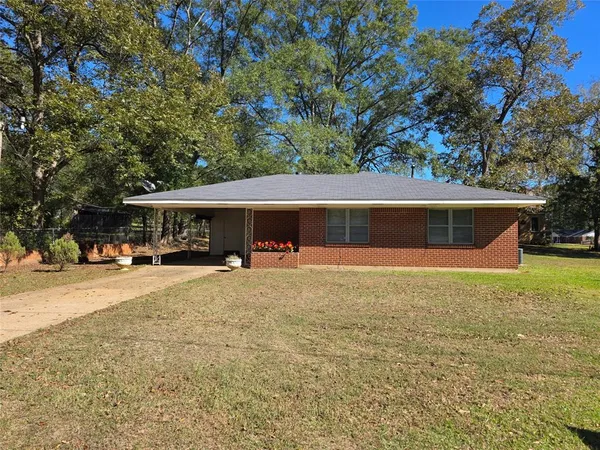 a front view of house with yard and trees in the background