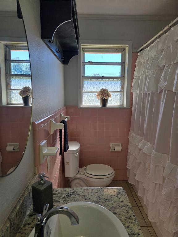 103 North Magnolia Street Plain Dealing, LA 71064 - Photo 19 of 26 Full bathroom with tile patterned flooring, a shower with shower curtain, vanity, tile walls, and wainscoting