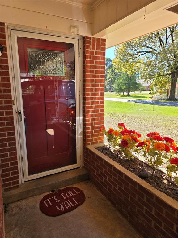 103 North Magnolia Street Plain Dealing, LA 71064 - Photo 4 of 26 Entrance to property featuring covered porch, brick siding, and a yard