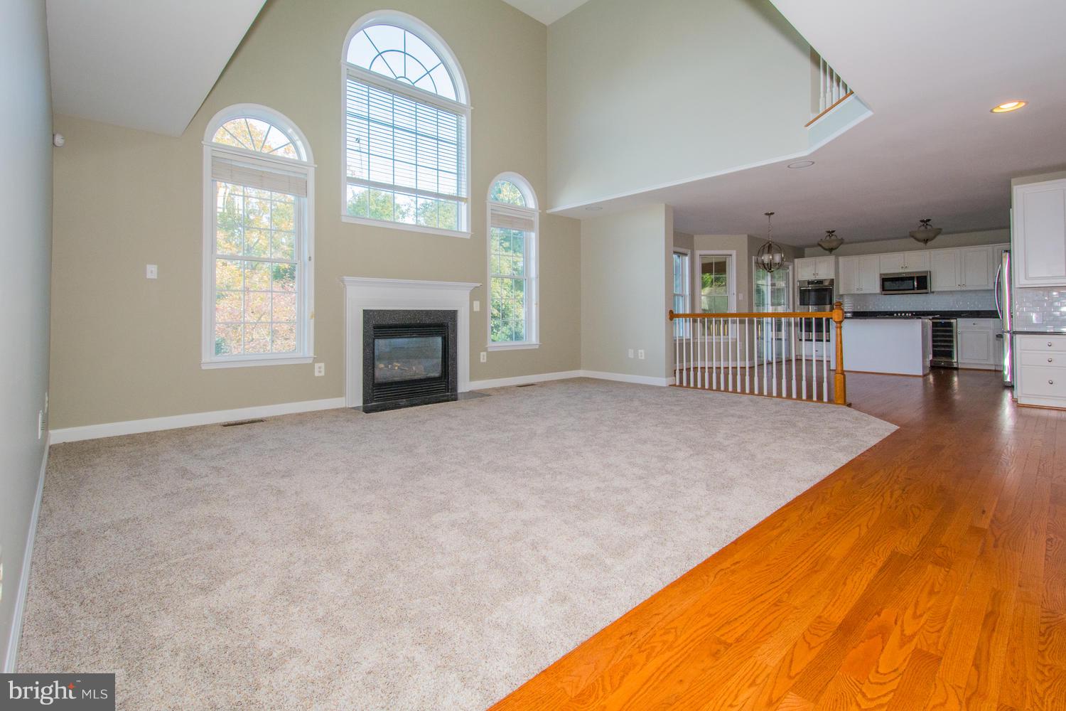 5986 Calvert Way Eldersburg, MD 21784 - Photo 2 of 40 an empty room with windows fireplace and wooden floor