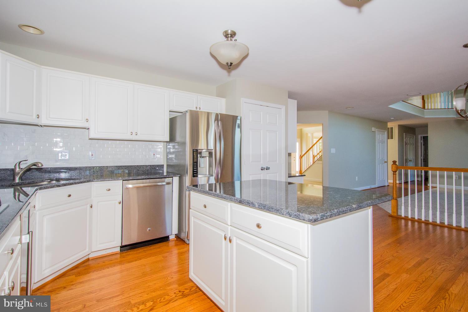 5986 Calvert Way Eldersburg, MD 21784 - Photo 8 of 40 a kitchen with stainless steel appliances granite countertop a sink dishwasher and white cabinets with wooden floor