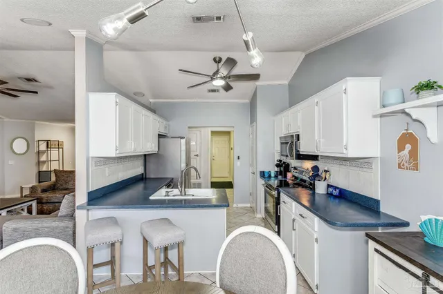 a kitchen with stainless steel appliances granite countertop a sink a stove a refrigerator cabinets and chairs