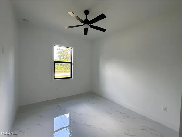 an empty room with ceiling fan and windows