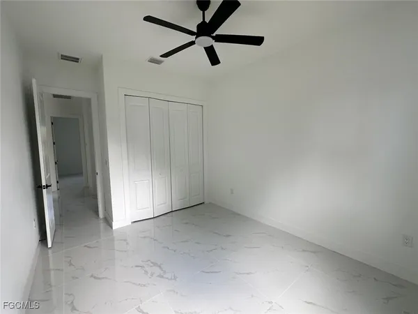 an empty room with a ceiling fan and carpet