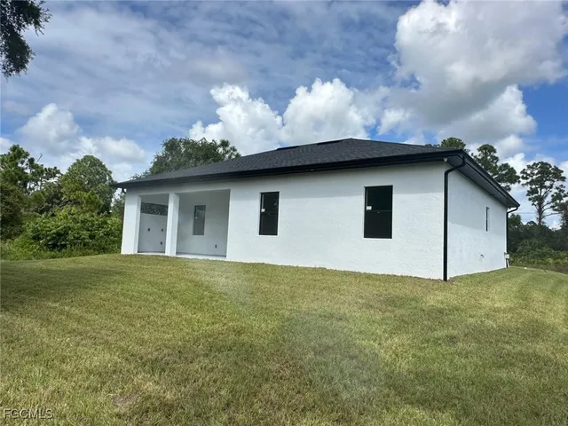 a white house that has a big yard with wooden fence