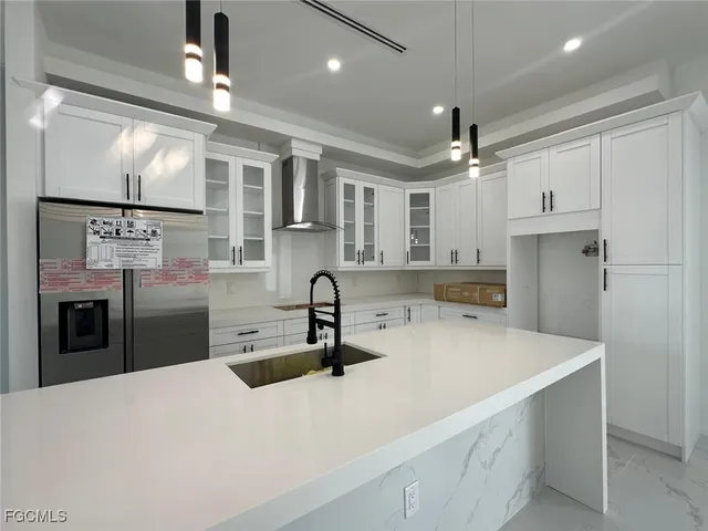 a kitchen with stainless steel appliances kitchen island a refrigerator sink and cabinets