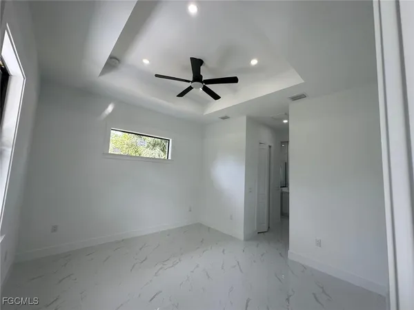 en empty room with windows and ceiling fan