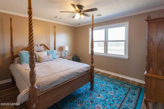 a bedroom with a bed dresser and wooden floor