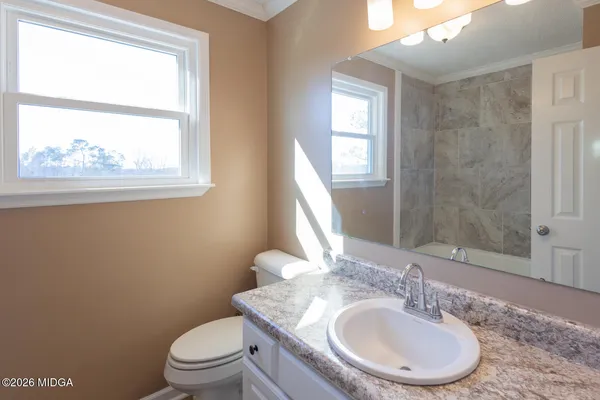 a bathroom with a toilet a sink a mirror and a window