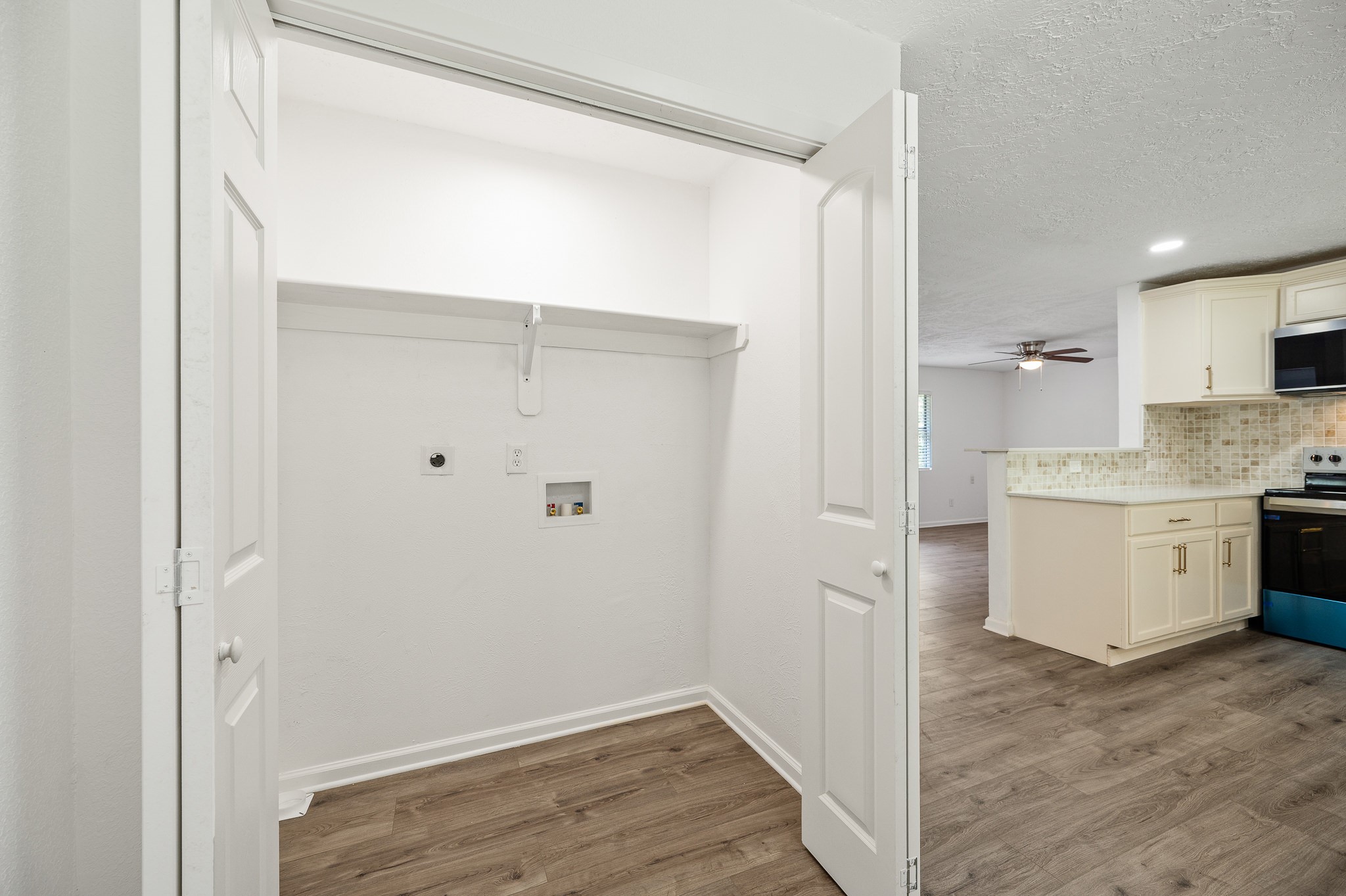 61 Hicks Loop West Cleveland, TX 77328 - Photo 11 of 38 Spacious laundry closet with convenient access to an open-concept kitchen and living area featuring modern appliances and elegant wood flooring.