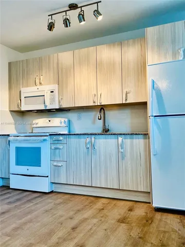 a view of kitchen with stainless steel appliances granite countertop a stove a refrigerator and a cabinets