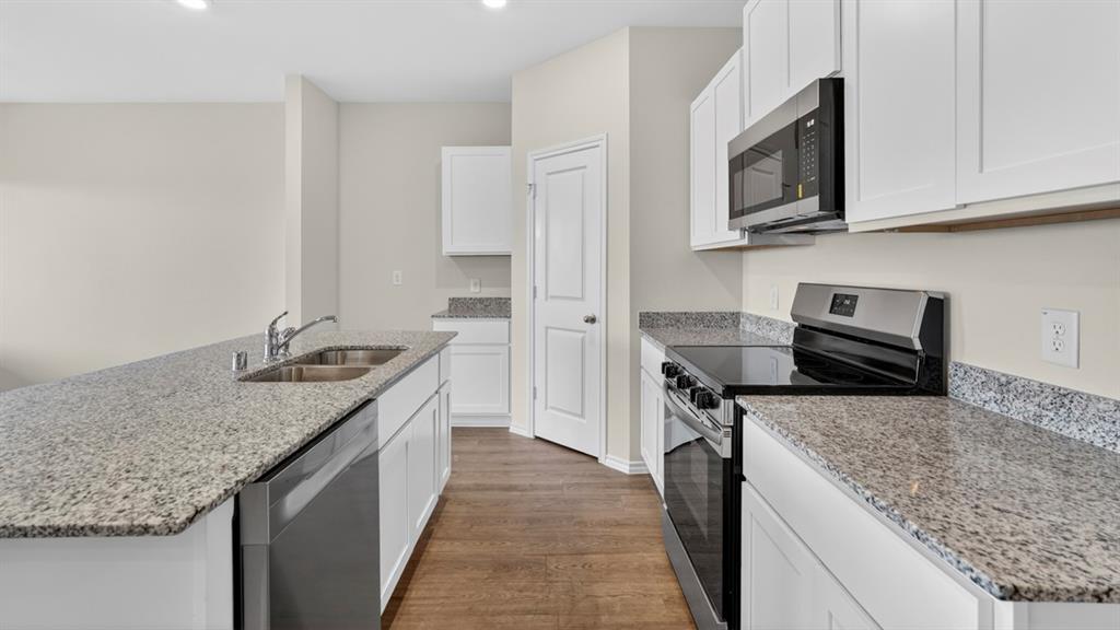 4008 Ripplewood Drive Lindale, TX 75771 - Photo 23 of 37 Kitchen featuring white cabinetry, granite countertops, stainless steel appliances, and wood-finish flooring