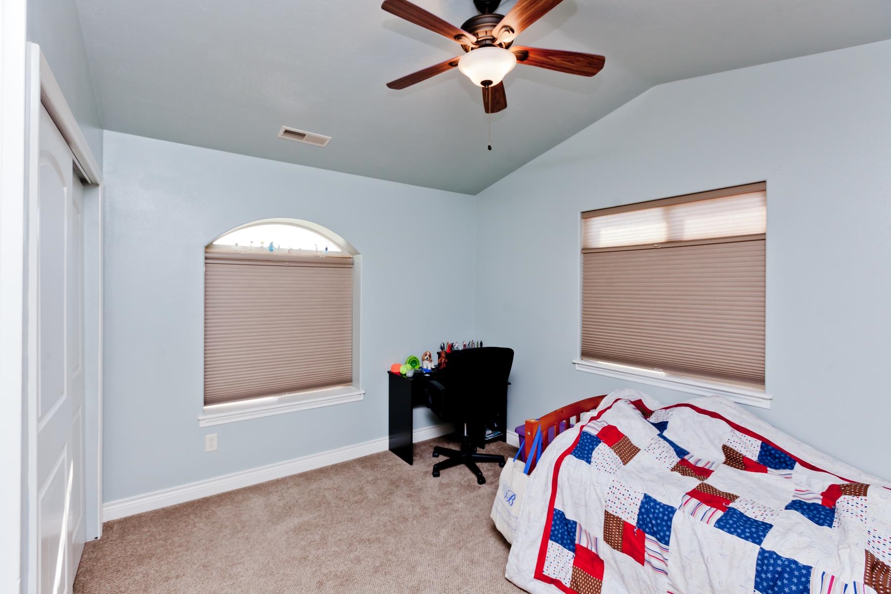1037 Wingate Drive Fruita, CO 81521 - Photo 24 of 42 a bedroom with a bed and a chandelier