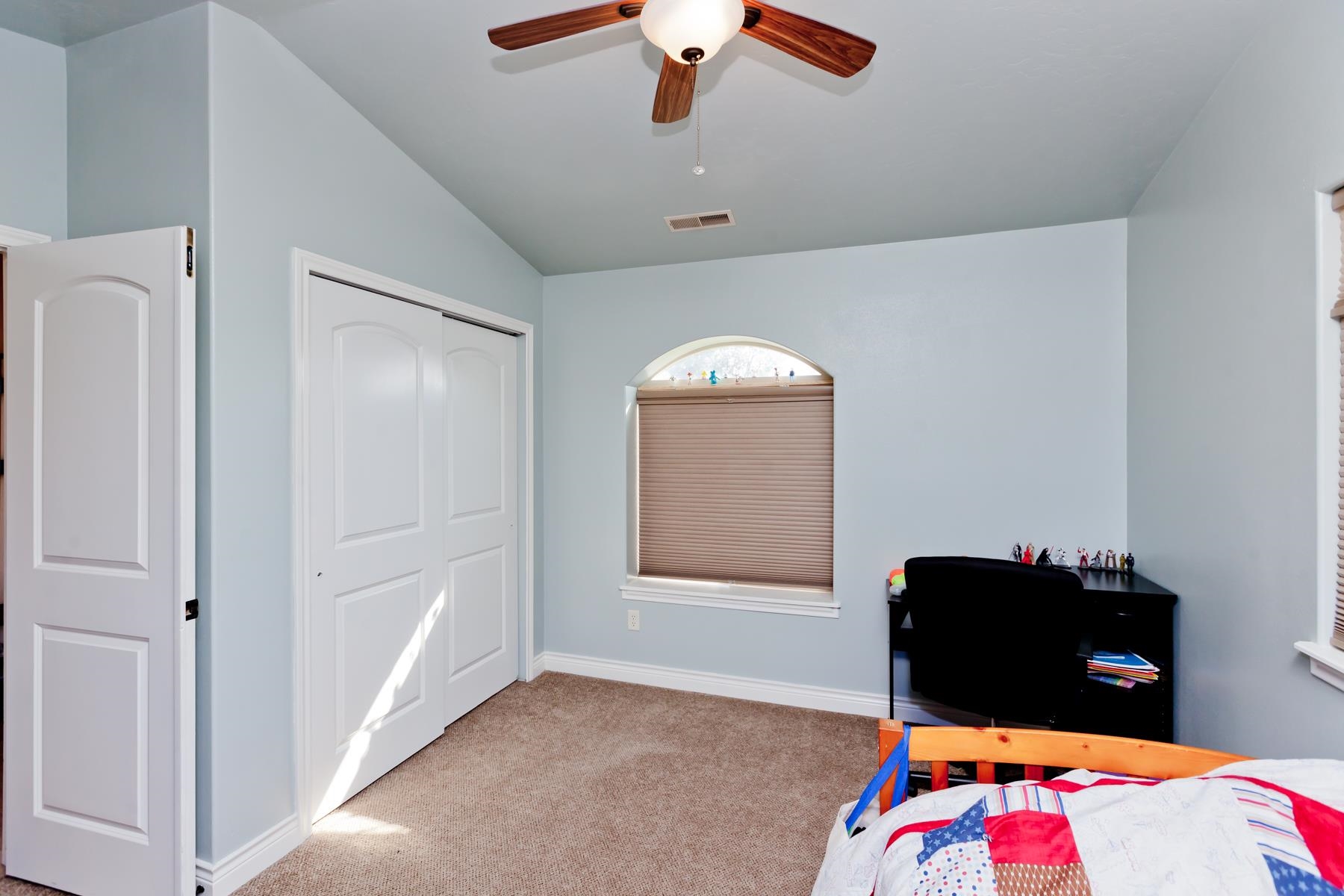1037 Wingate Drive Fruita, CO 81521 - Photo 28 of 42 a bedroom with a bed and a chandelier