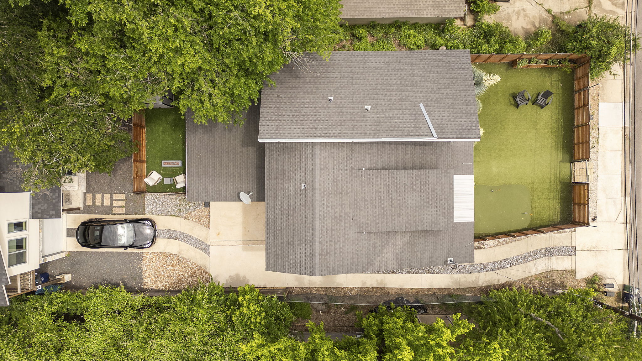 5204 Samuel Huston Avenue Austin, TX 78721 - Photo 38 of 38 Expansive aerial view showcasing the property's exterior, including a large gray roof, a paved driveway with decorative stone accents, and a fenced backyard with artificial turf