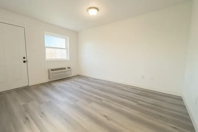 an empty room with wooden floor and windows