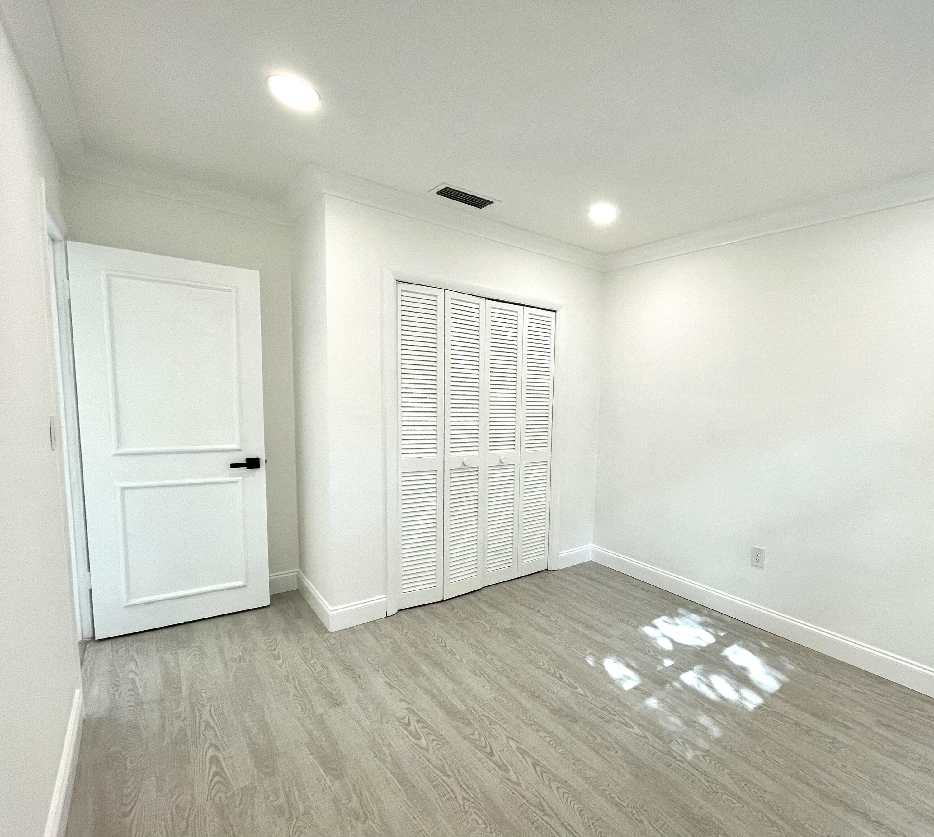 861 Northwest 7th Street Boca Raton, FL 33486 - Photo 13 of 18 an empty room with wooden floor & windows and bathroom