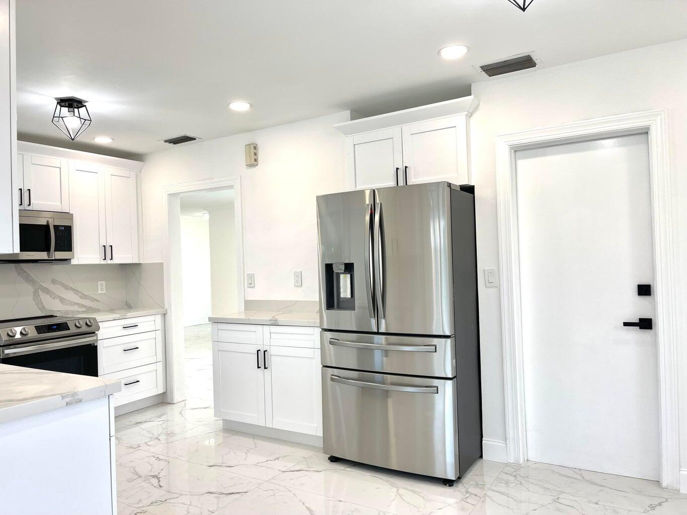 861 Northwest 7th Street Boca Raton, FL 33486 - Photo 4 of 18 a kitchen with stainless steel appliances a refrigerator sink and stove