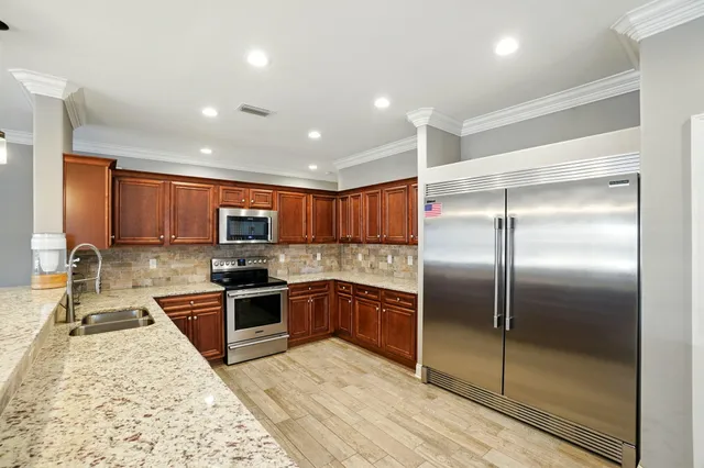 a kitchen with stainless steel appliances granite countertop a stove top oven a sink and a refrigerator