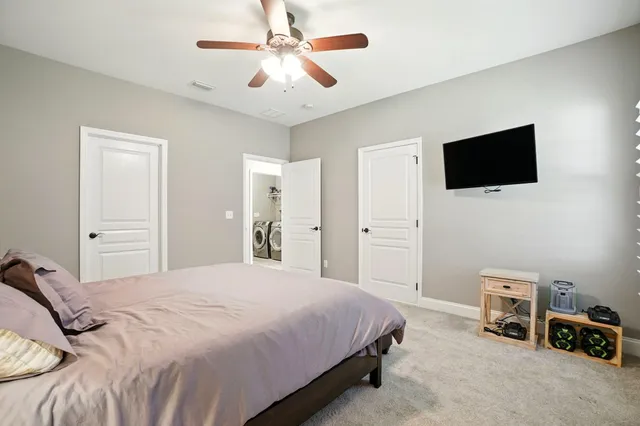 a bedroom with a bed a flat screen tv and a chandelier