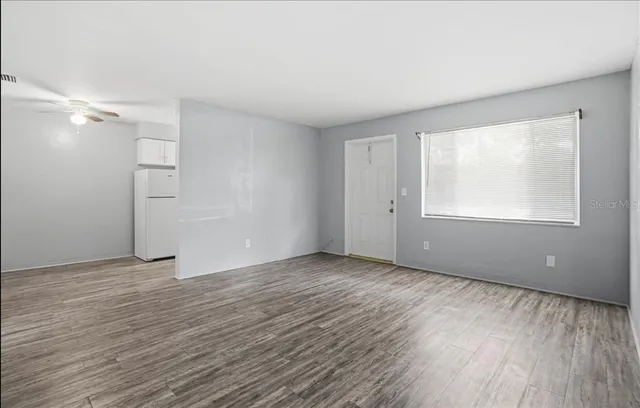 a view of an empty room with wooden floor and a window