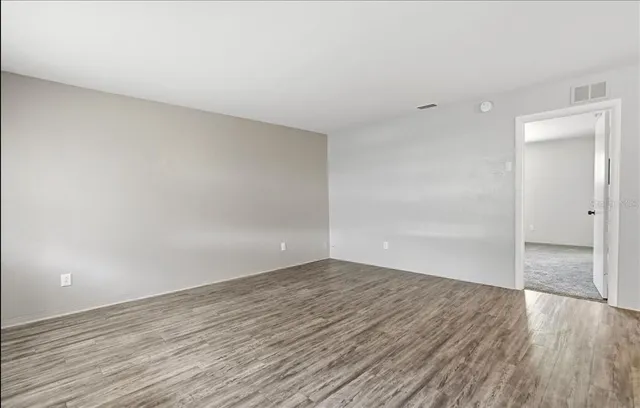 a view of an empty room with wooden floor and closet