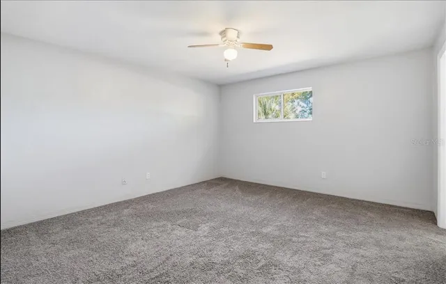 an empty room with a ceiling fan and window