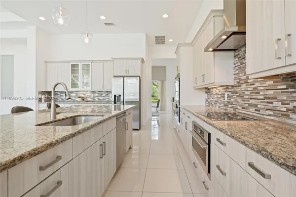 a large kitchen with stainless steel appliances granite countertop a lot of counter space and a sink